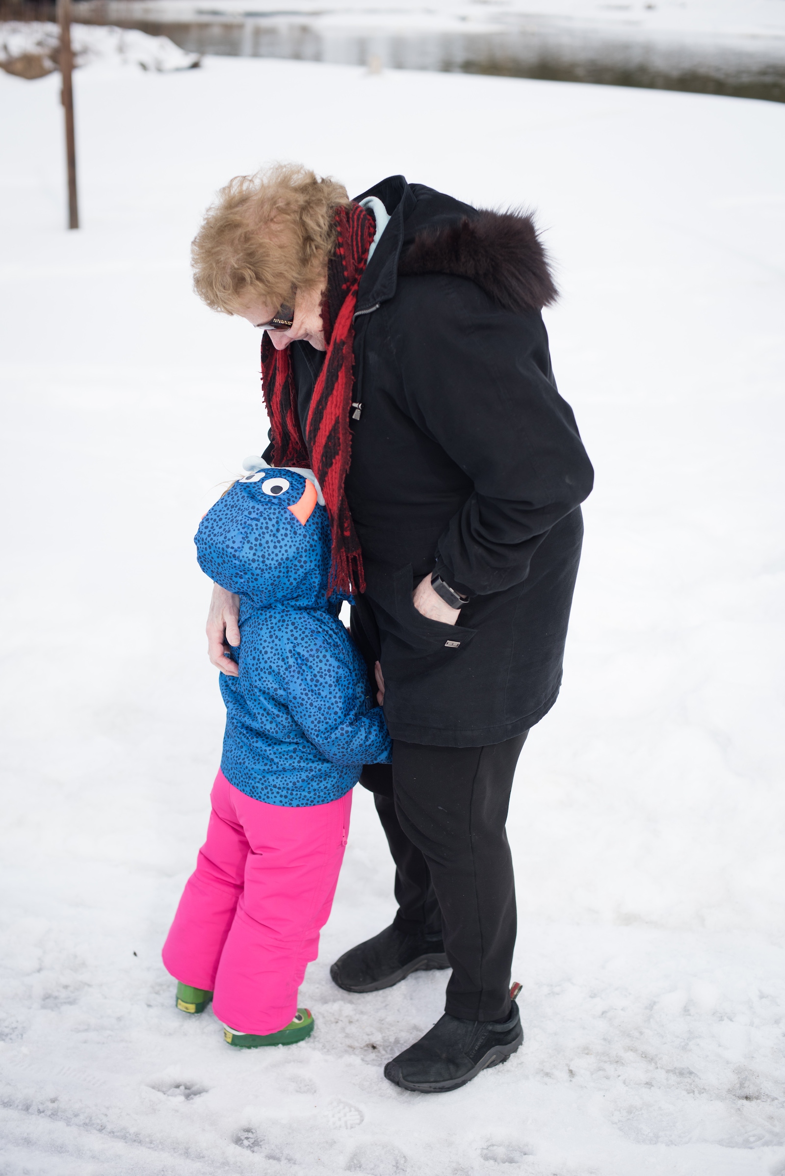 a young girl hugs a woman outside in the snow