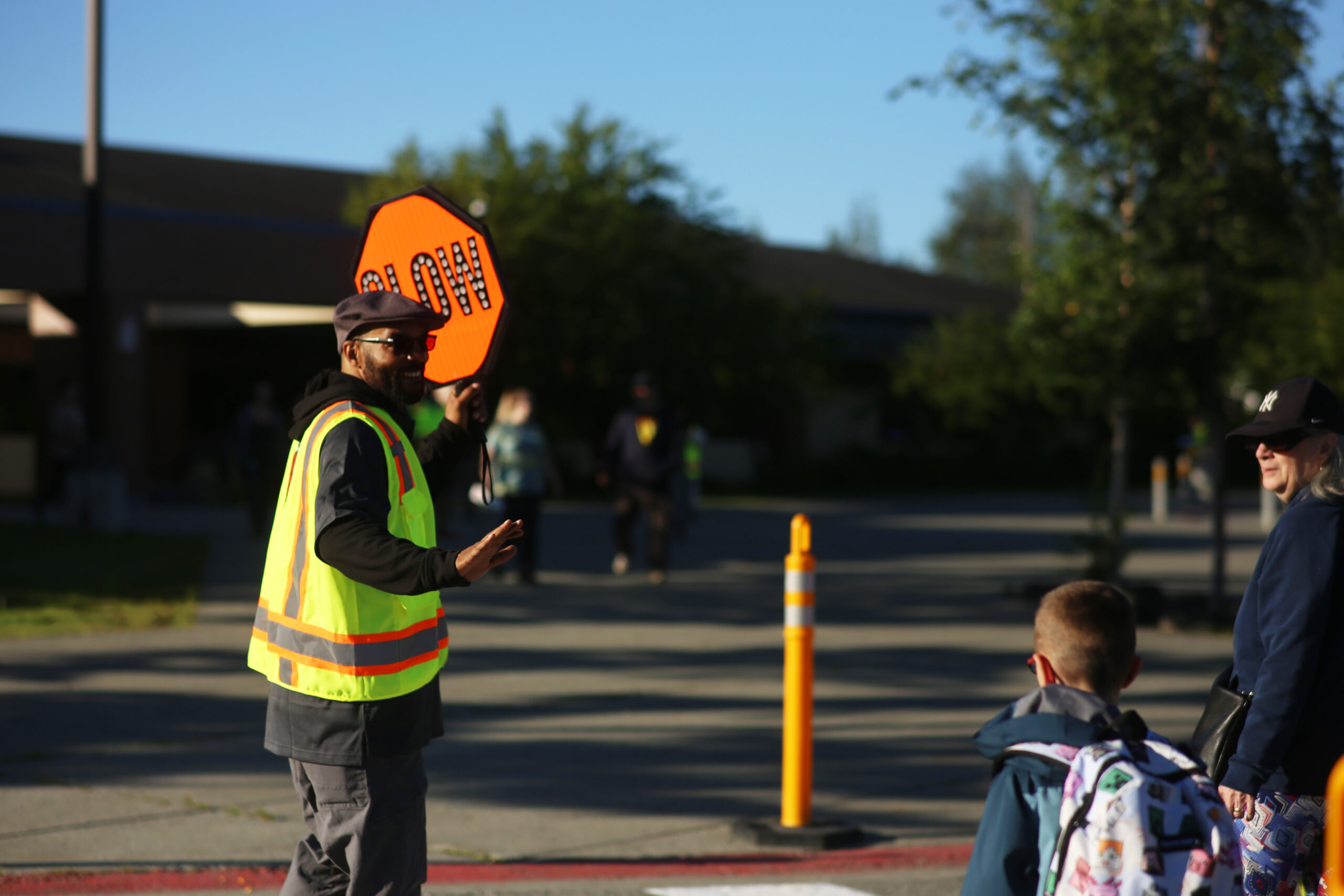 Ryan Marcey holds a stop sign and greets a student and parent as they cross