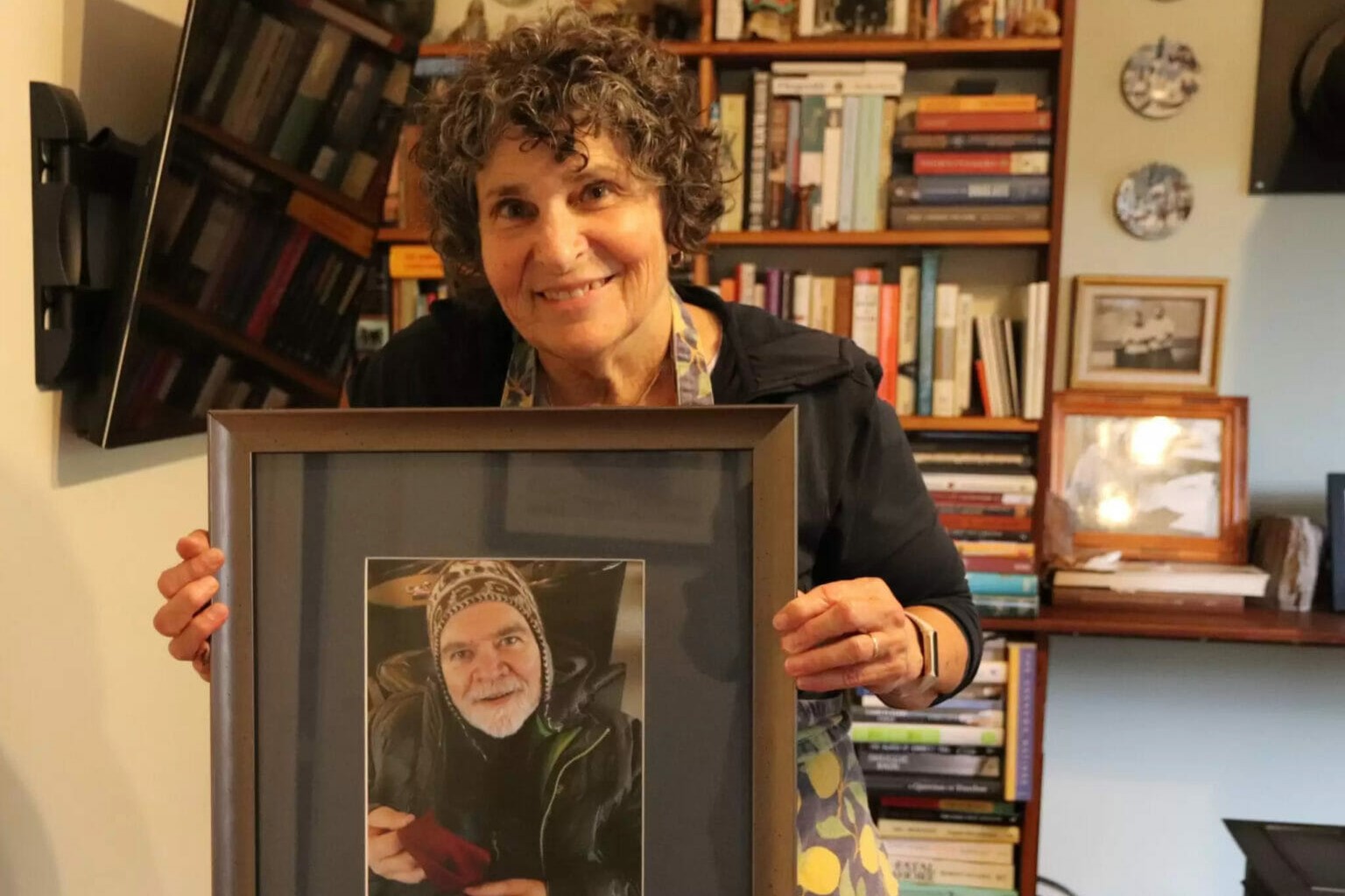 a woman holds a photograph of a man