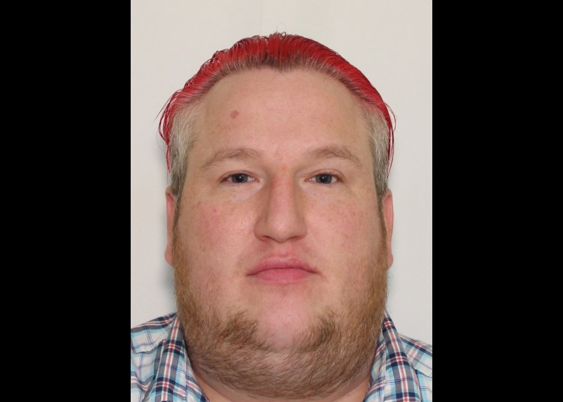 Mugshot of a white man with slicked back red hair