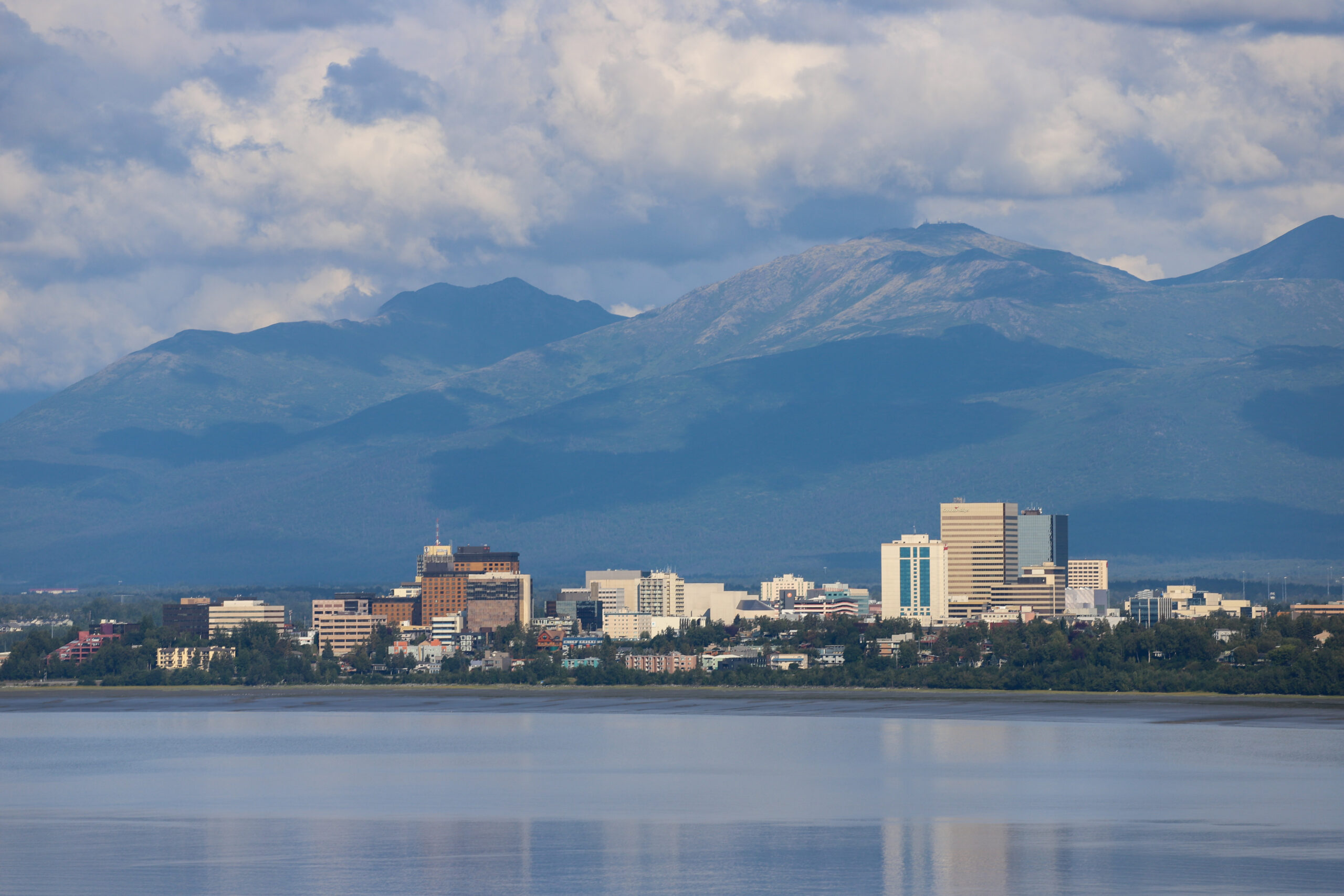 Downtown Anchorage, with water in the foreground and mountains behind.