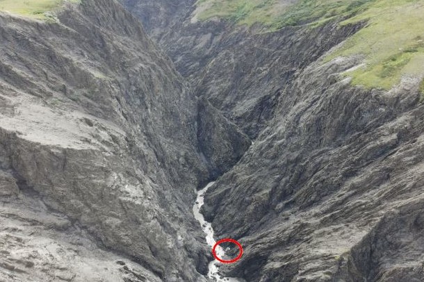 an airplane crash site, with the plane circled in red at the bottom of a steep ravine