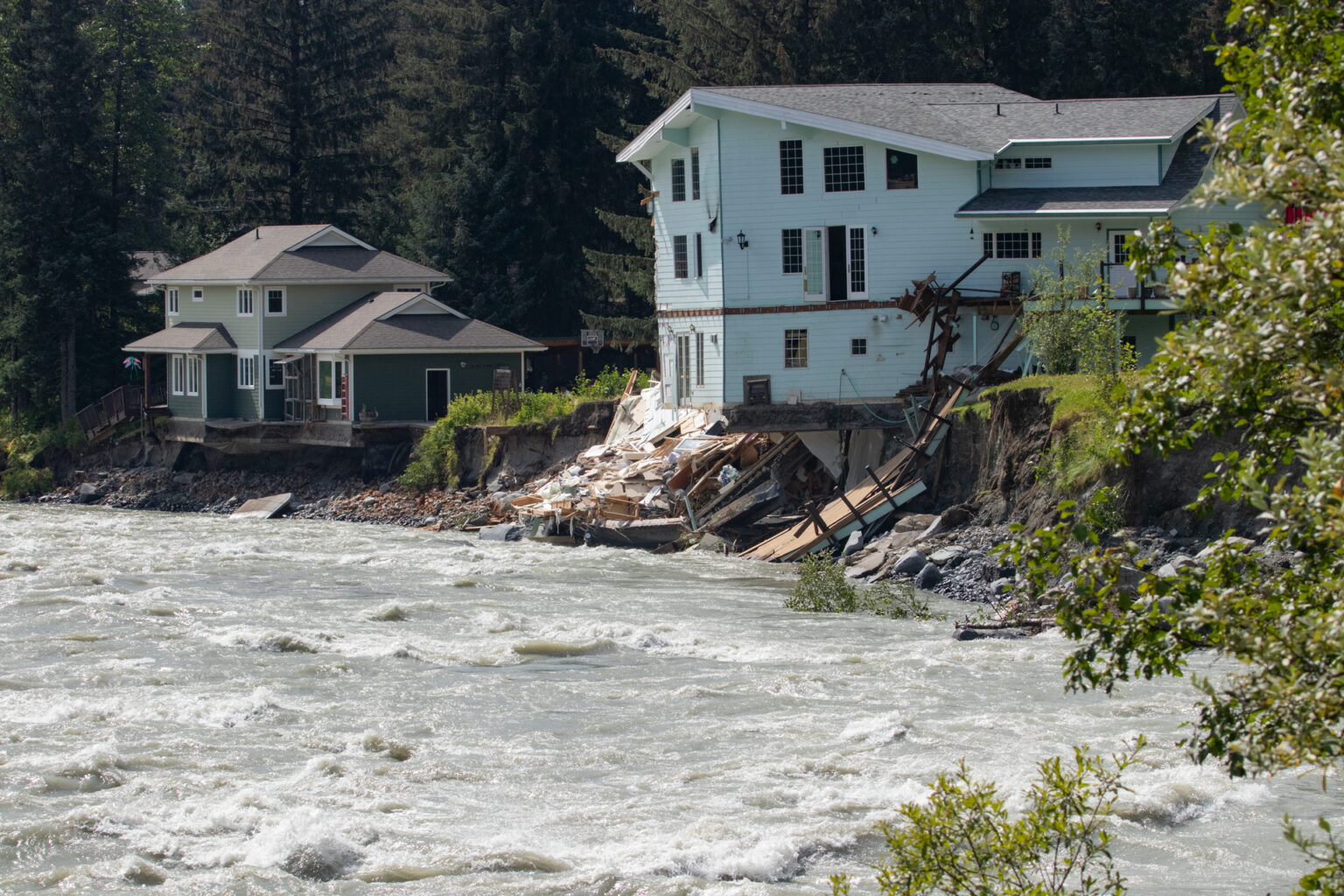 two homes in juneau, partially collapsing into a river