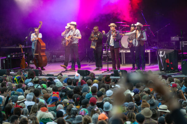 A country band plays an outdoor concert for a large audience.