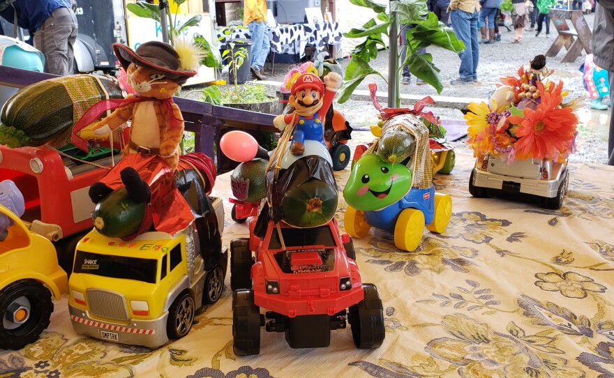 toy cars on a table with zucchini and figurines on them