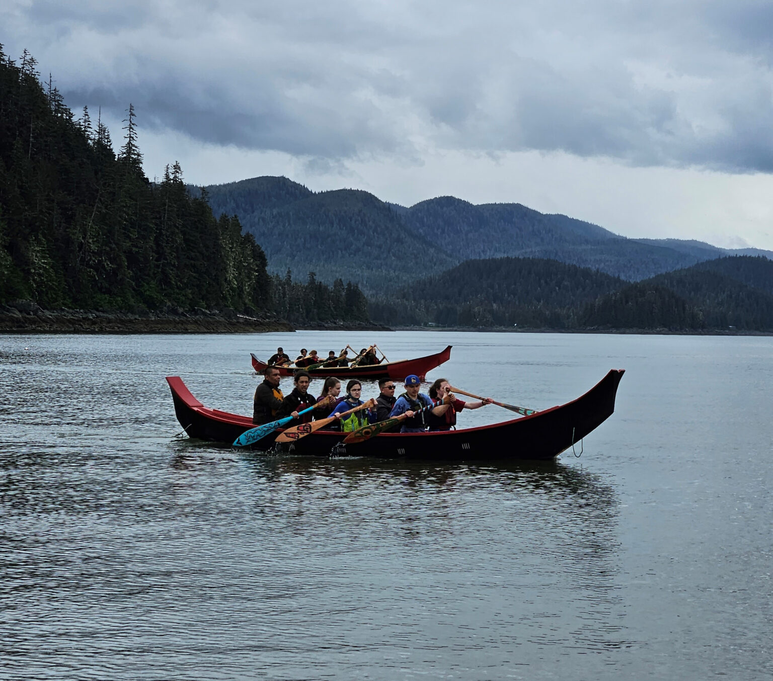 people paddle a canoe, with mountains in the background