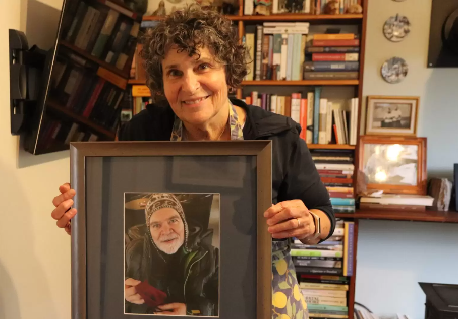 A woman holds a framed photo of her late husband.