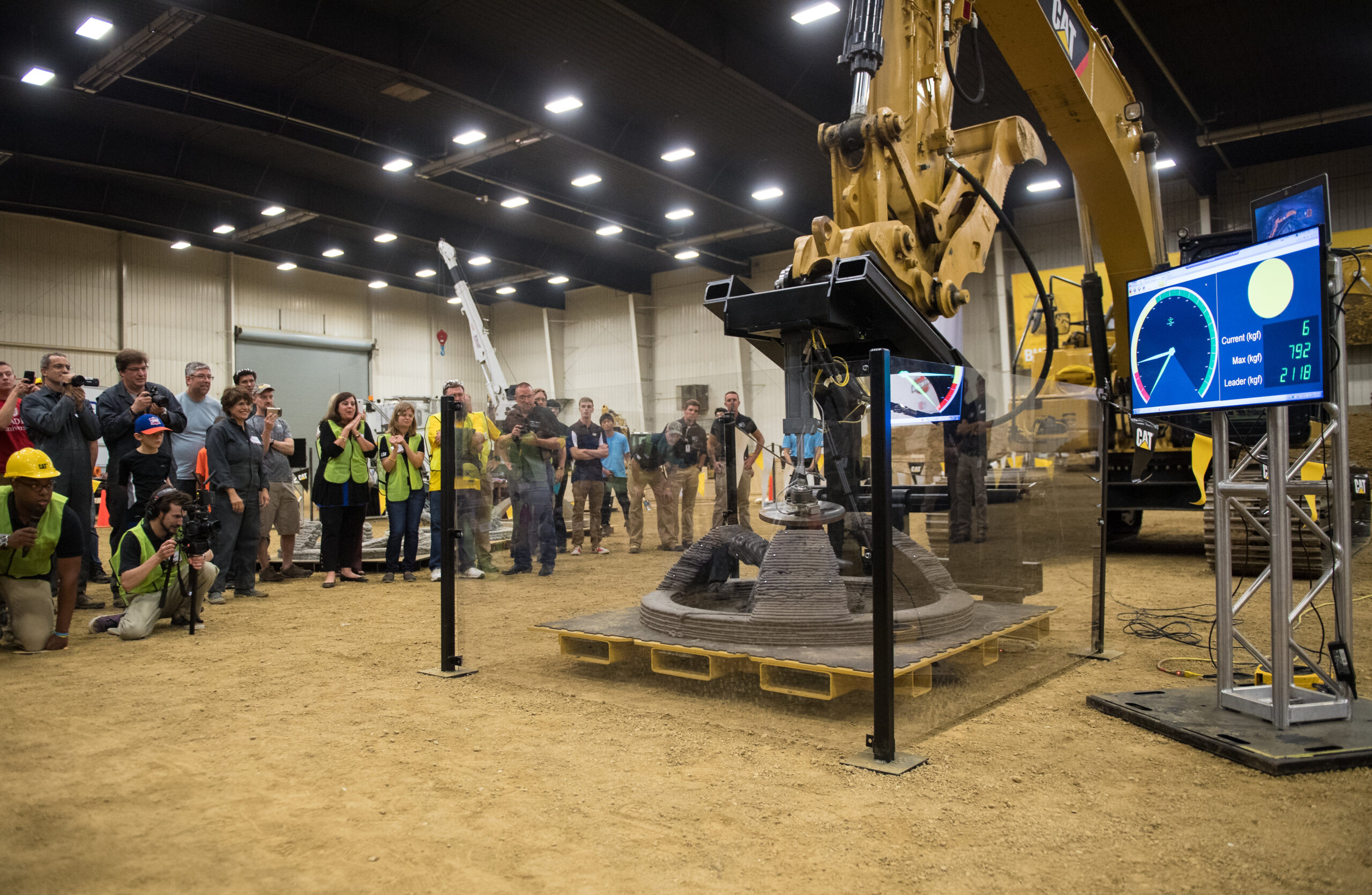 a crowd watches heavy machinery crush a concrete structure