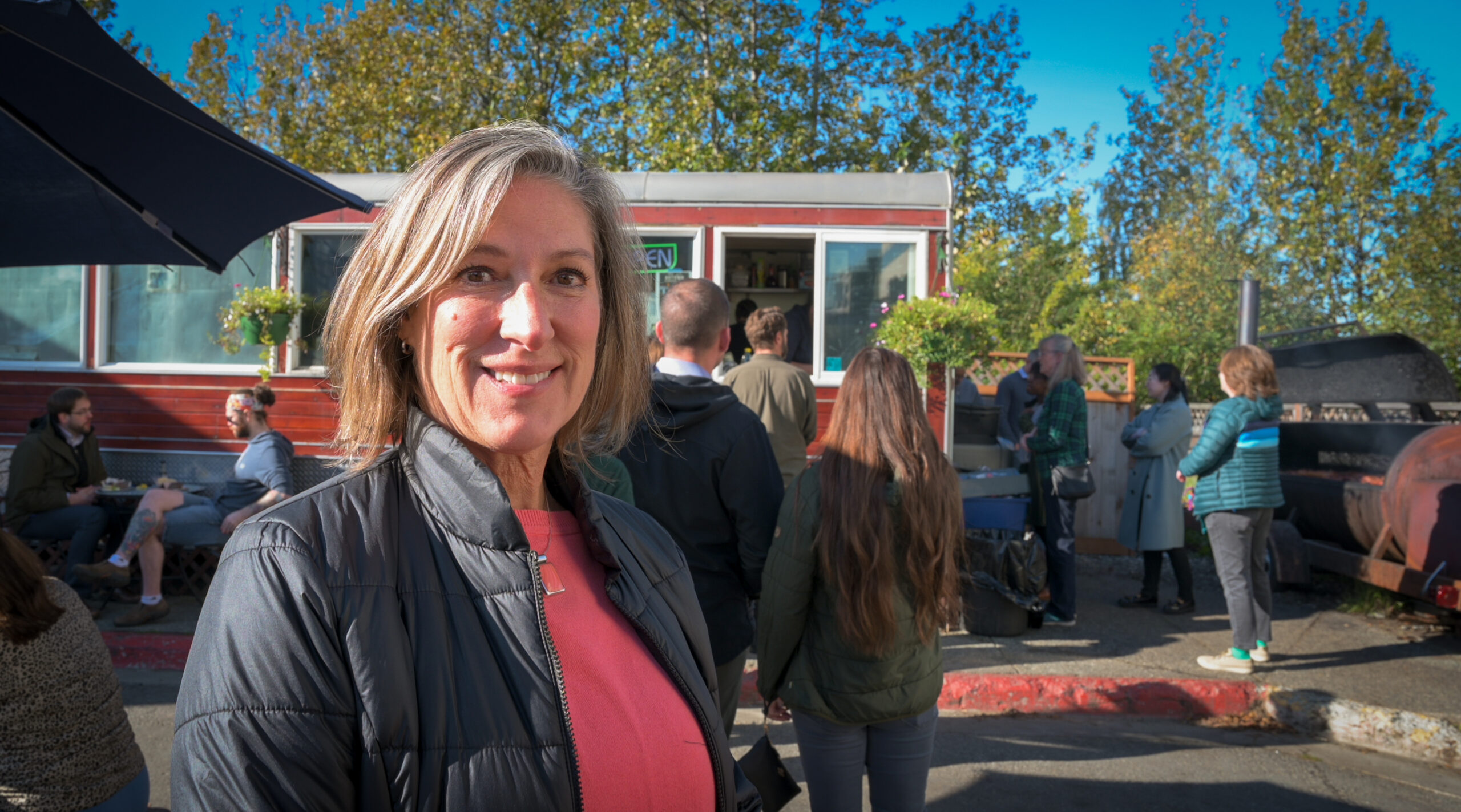 A woman in black puffy jacket outside a food truck.