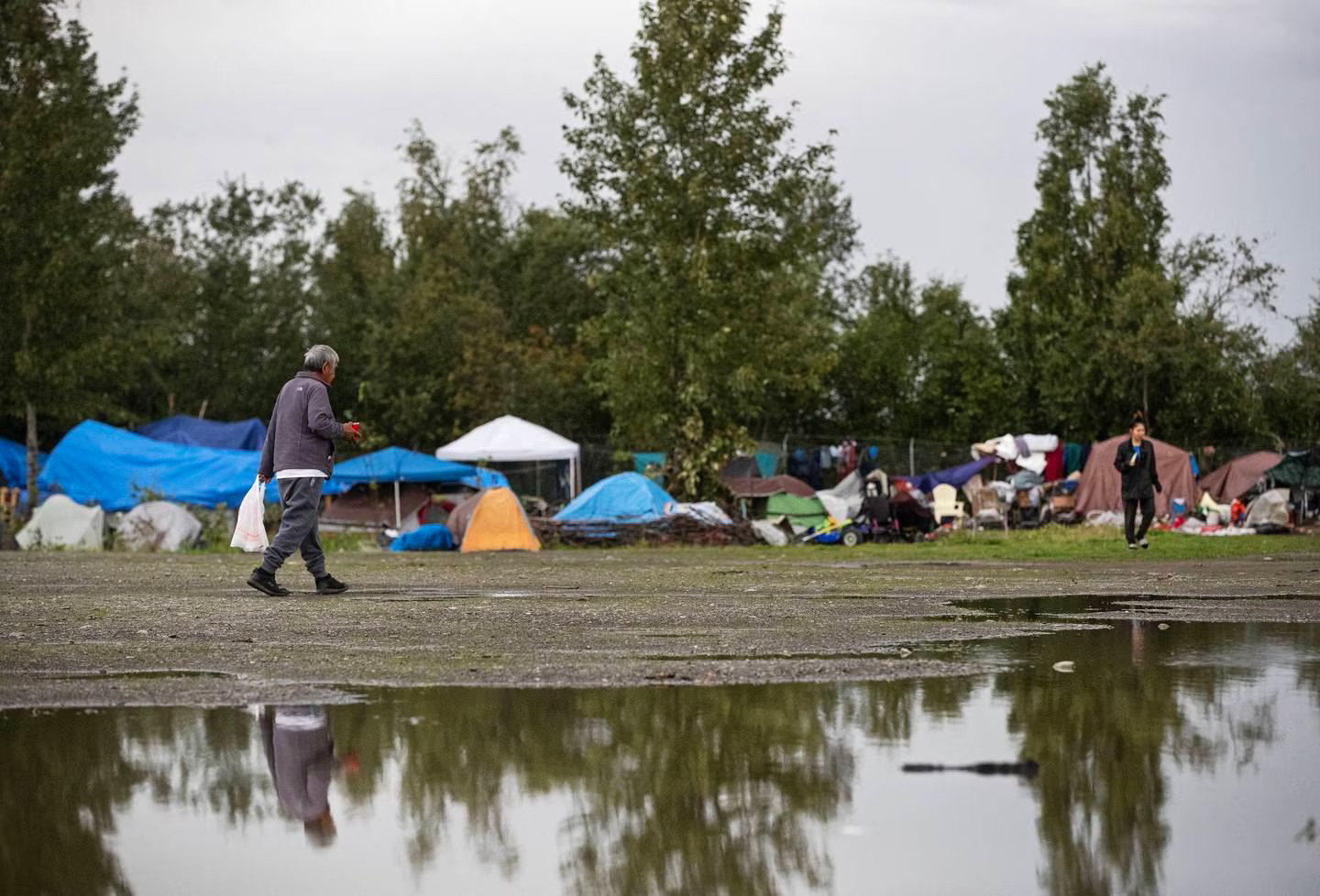 a person walks near a muddy and wet campsite