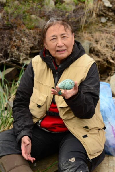 a woman holds up a blue egg