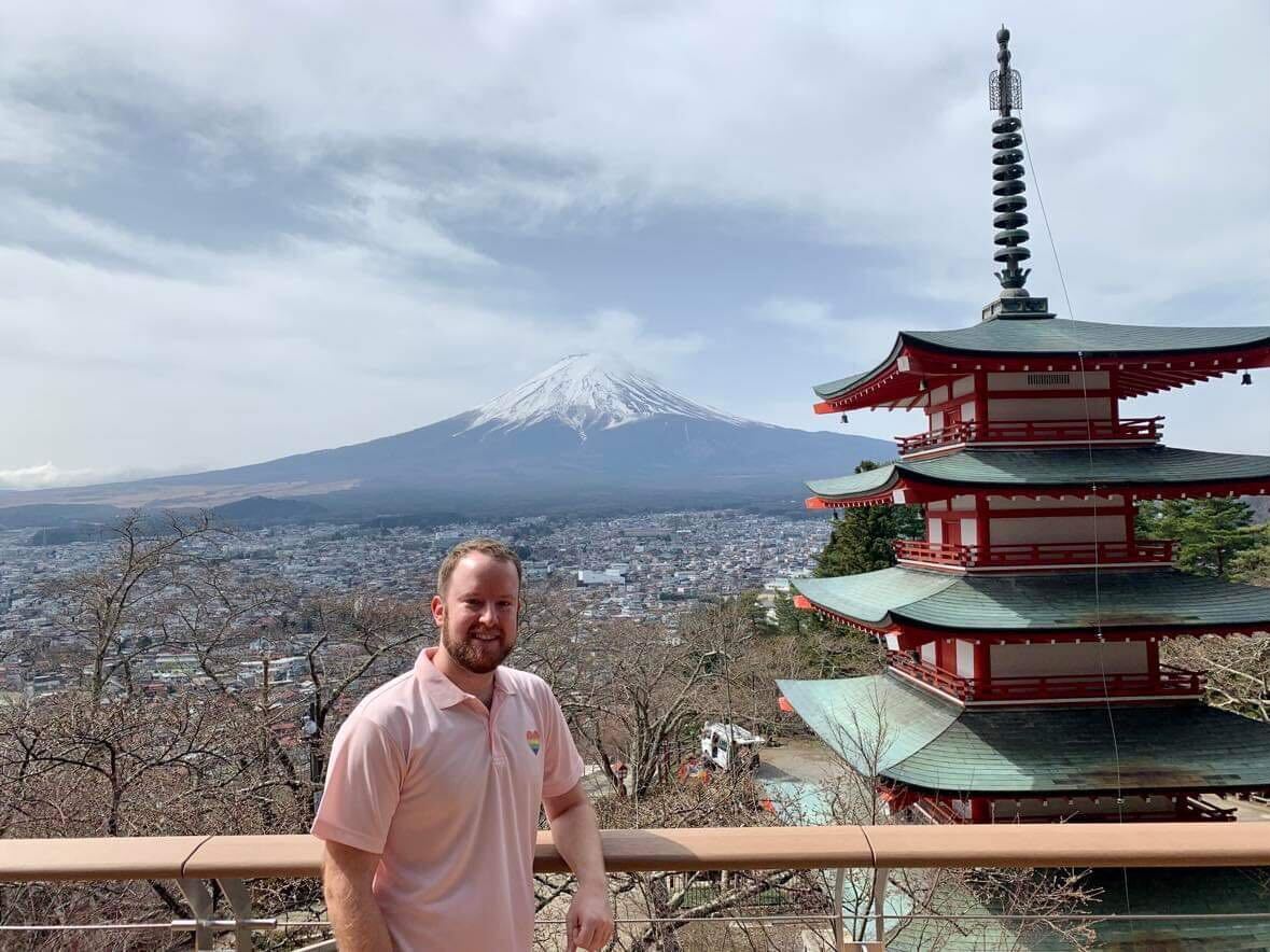 A man by a pagoda with Mt. Fuji in the background