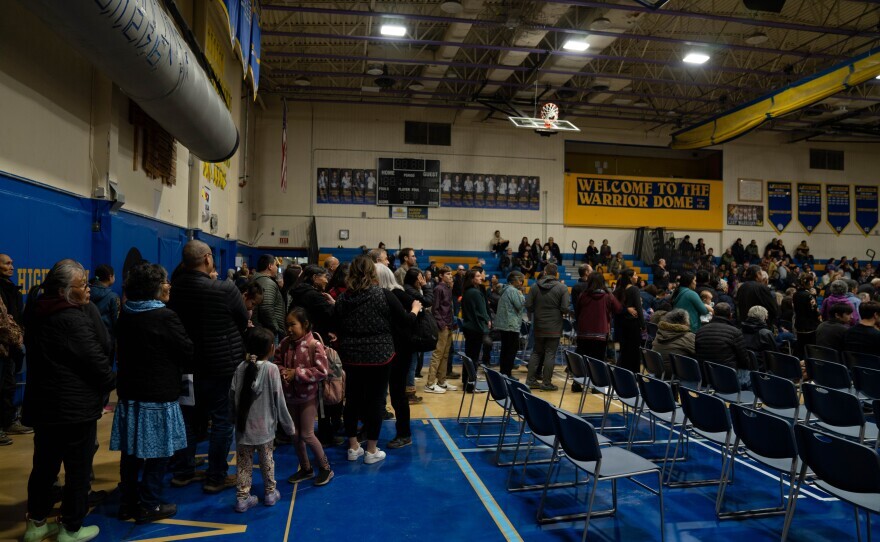 people stand in a long line in a school gym