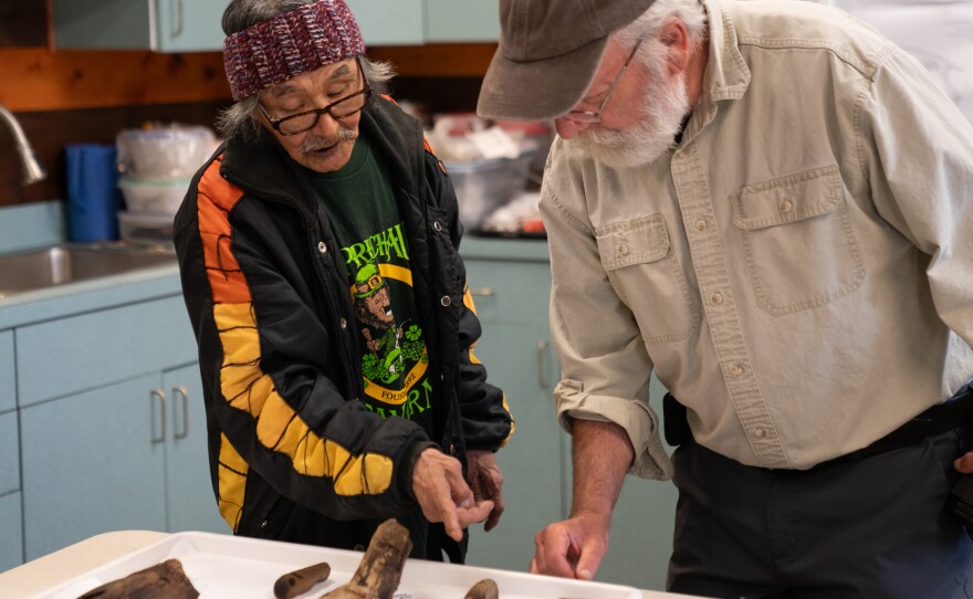 two people look at artifacts on a table, inside