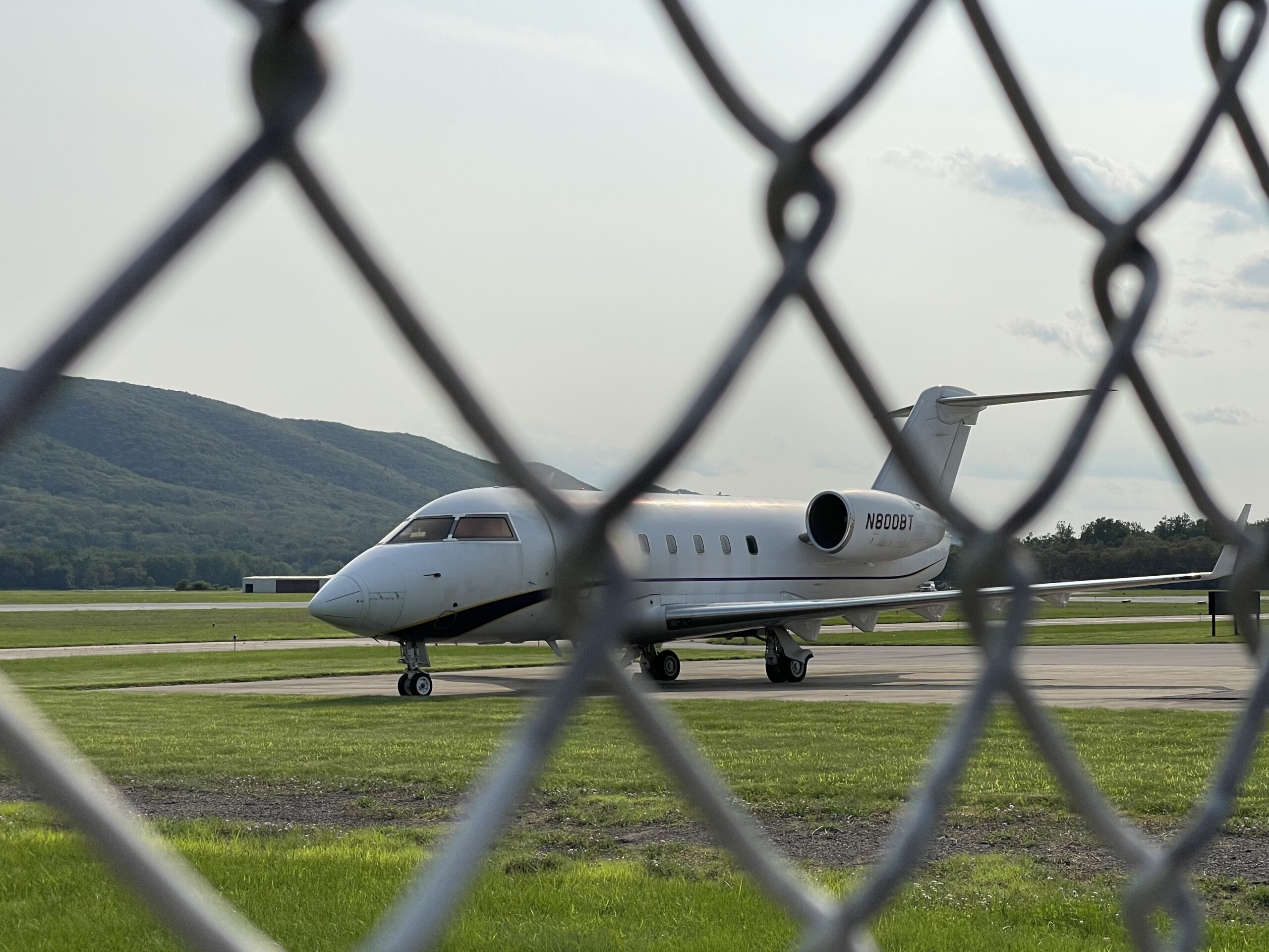 a plan on a runway, as seen from behind a fence