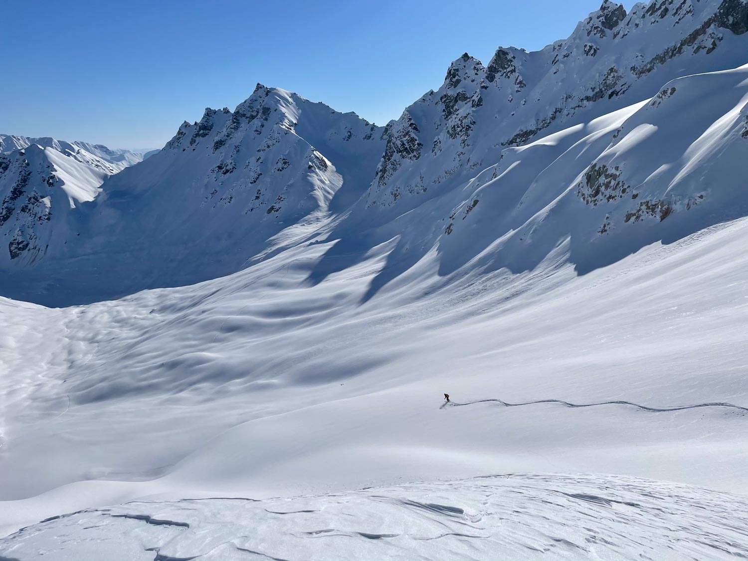 A skier makes tracks on a snowy mountainside