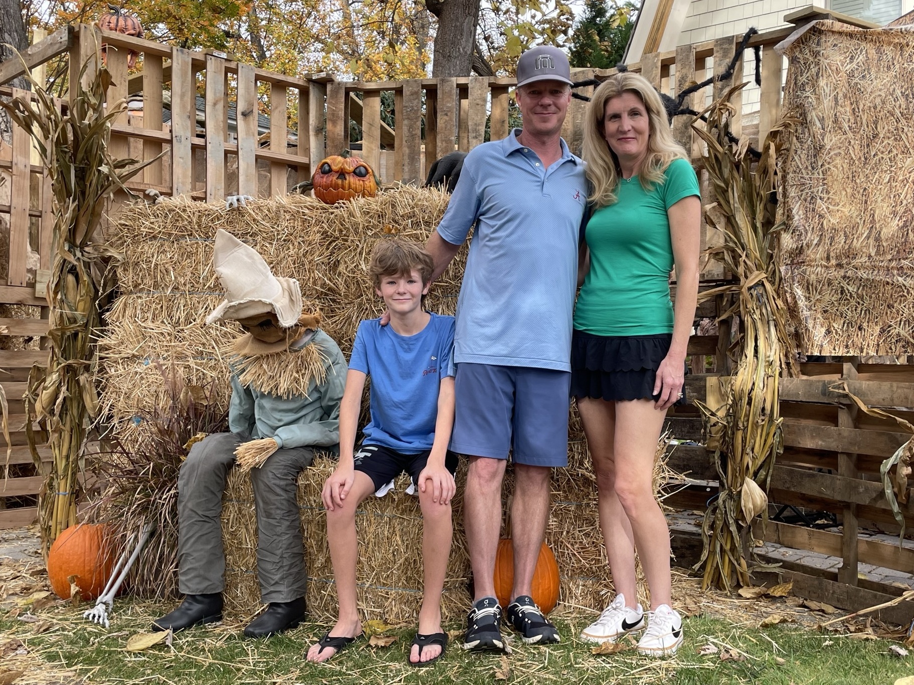 a family poses next to a scarecrow