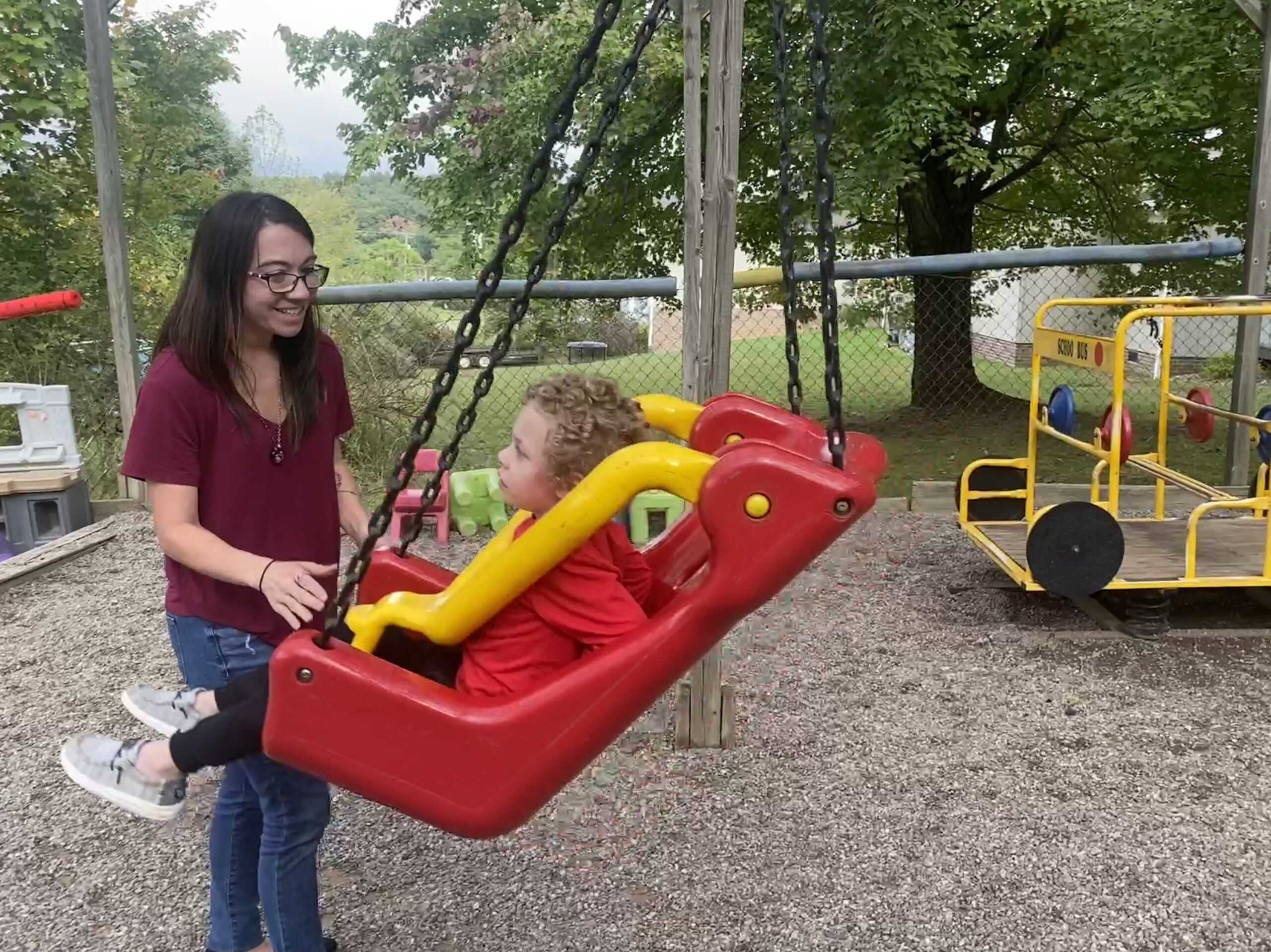 a woman pushes a child on a swing