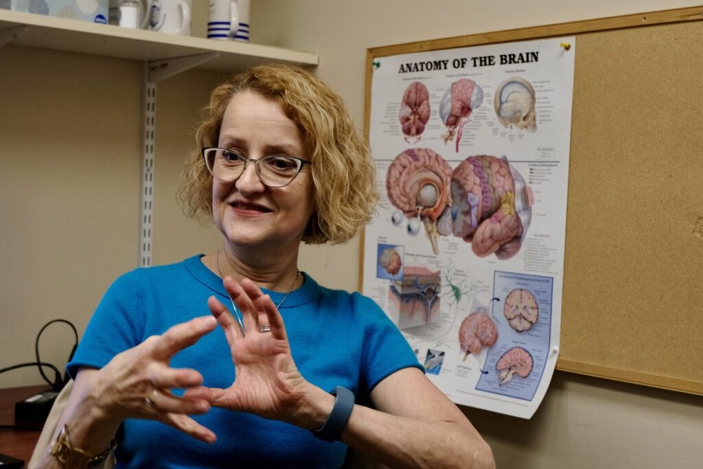 a woman holds out her hands in front of a brain poster