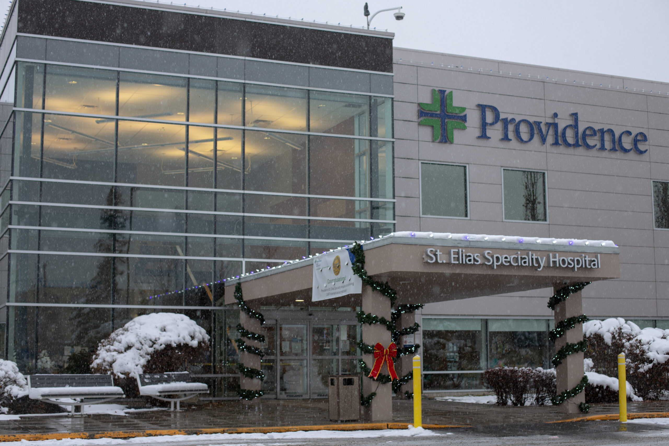 The front entrance of St. Elias Specialty Hospital in Anchorage displays holiday decorations on a snowy afternoon.