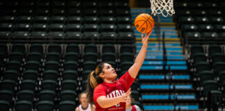 A woman in red short throws a basketball.