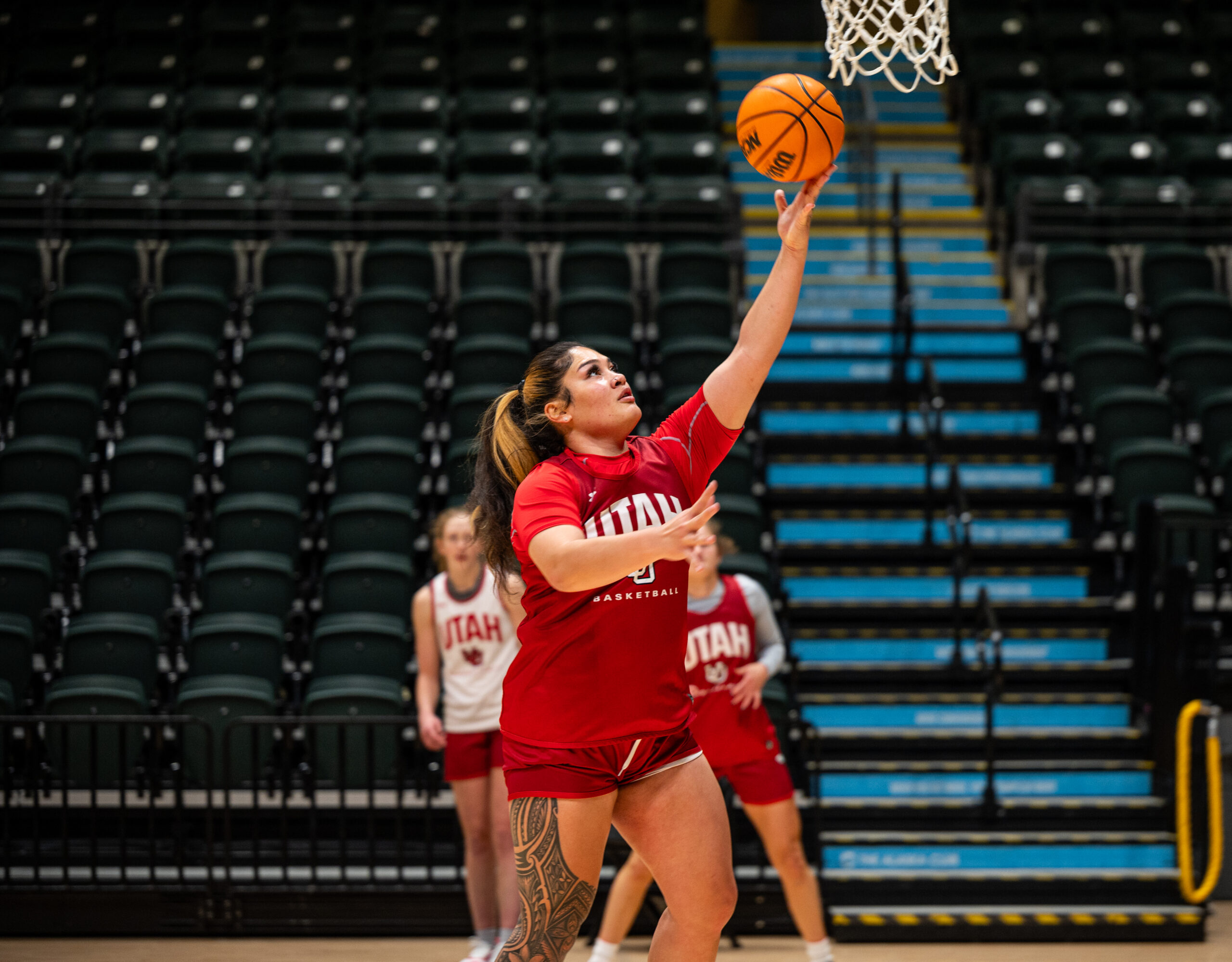 A woman in red short throws a basketball.