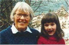 A woman with gray hair and glasses poses with a young girl.