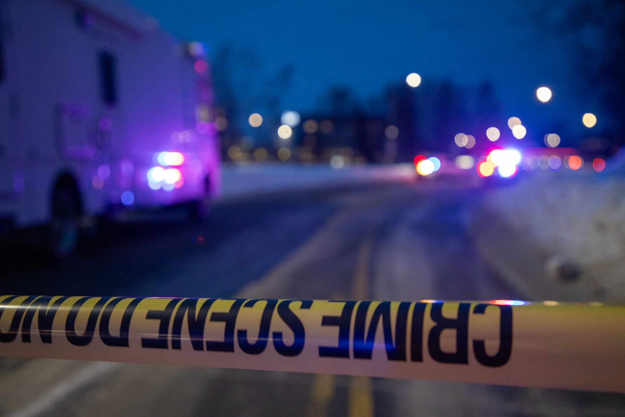 Crime scene tape with red and blue police lights.