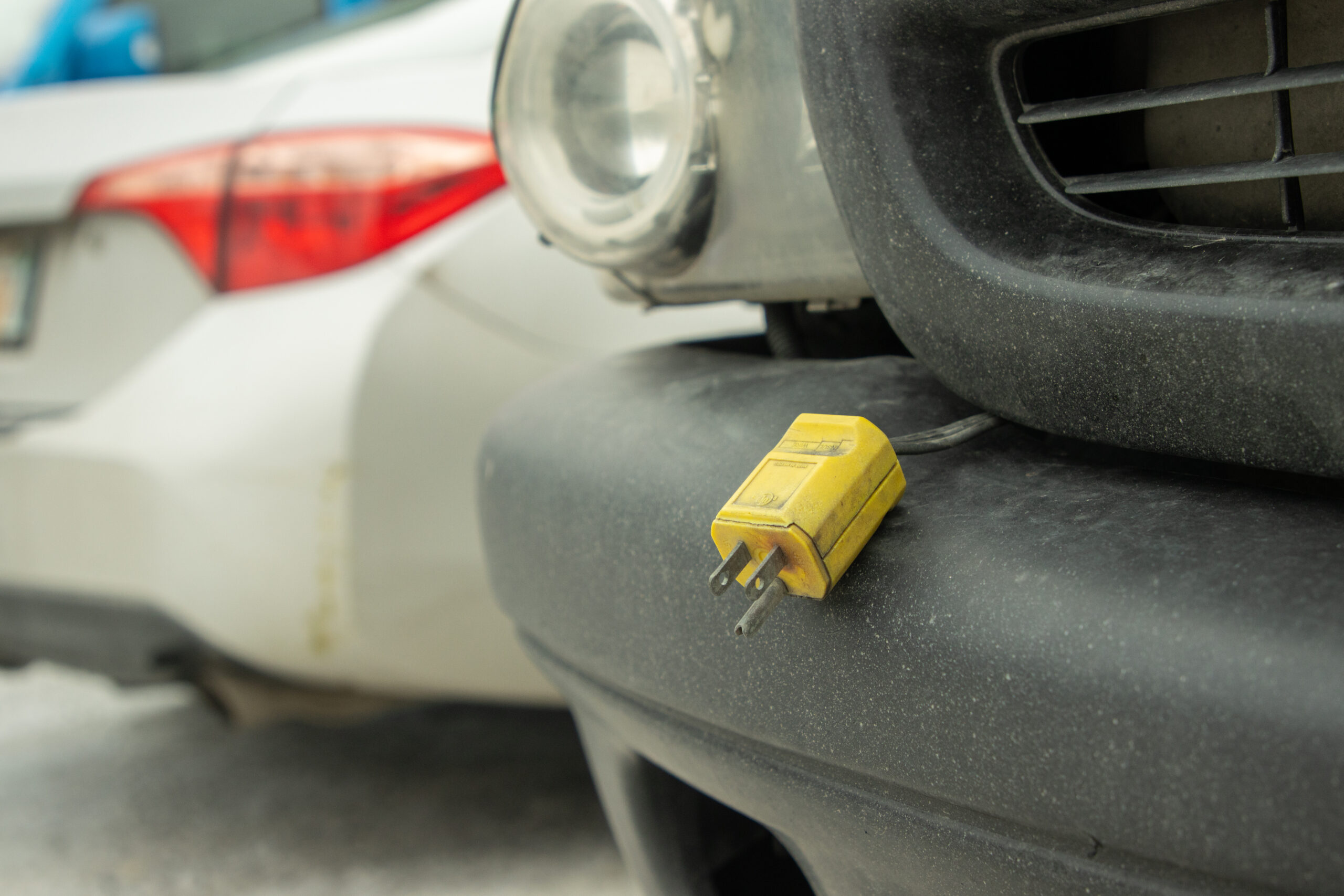 A yellow plug hangs from the front of a black truck