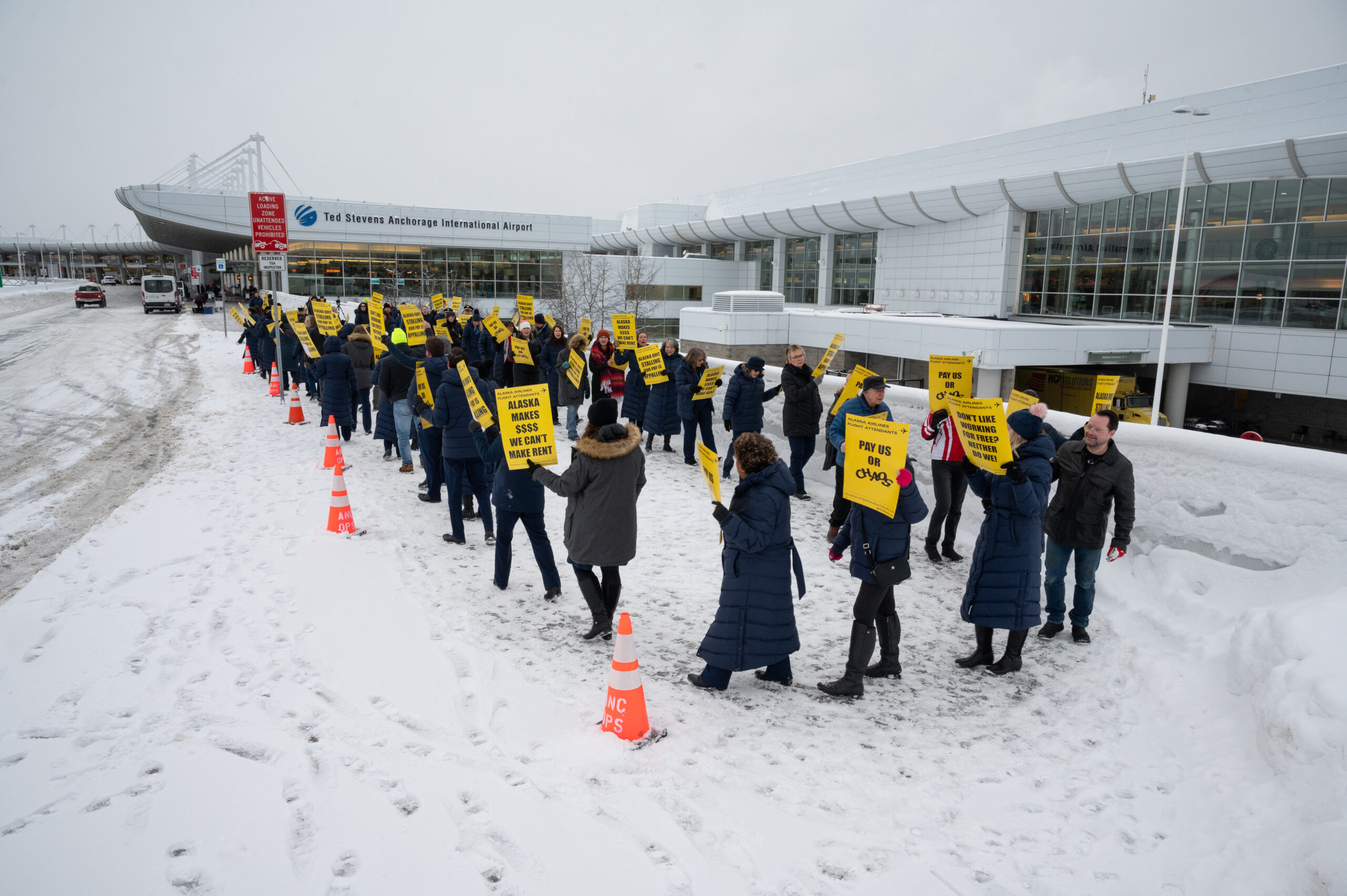 Flight attendants march in a picket line in front of Ted Stevens International Airport