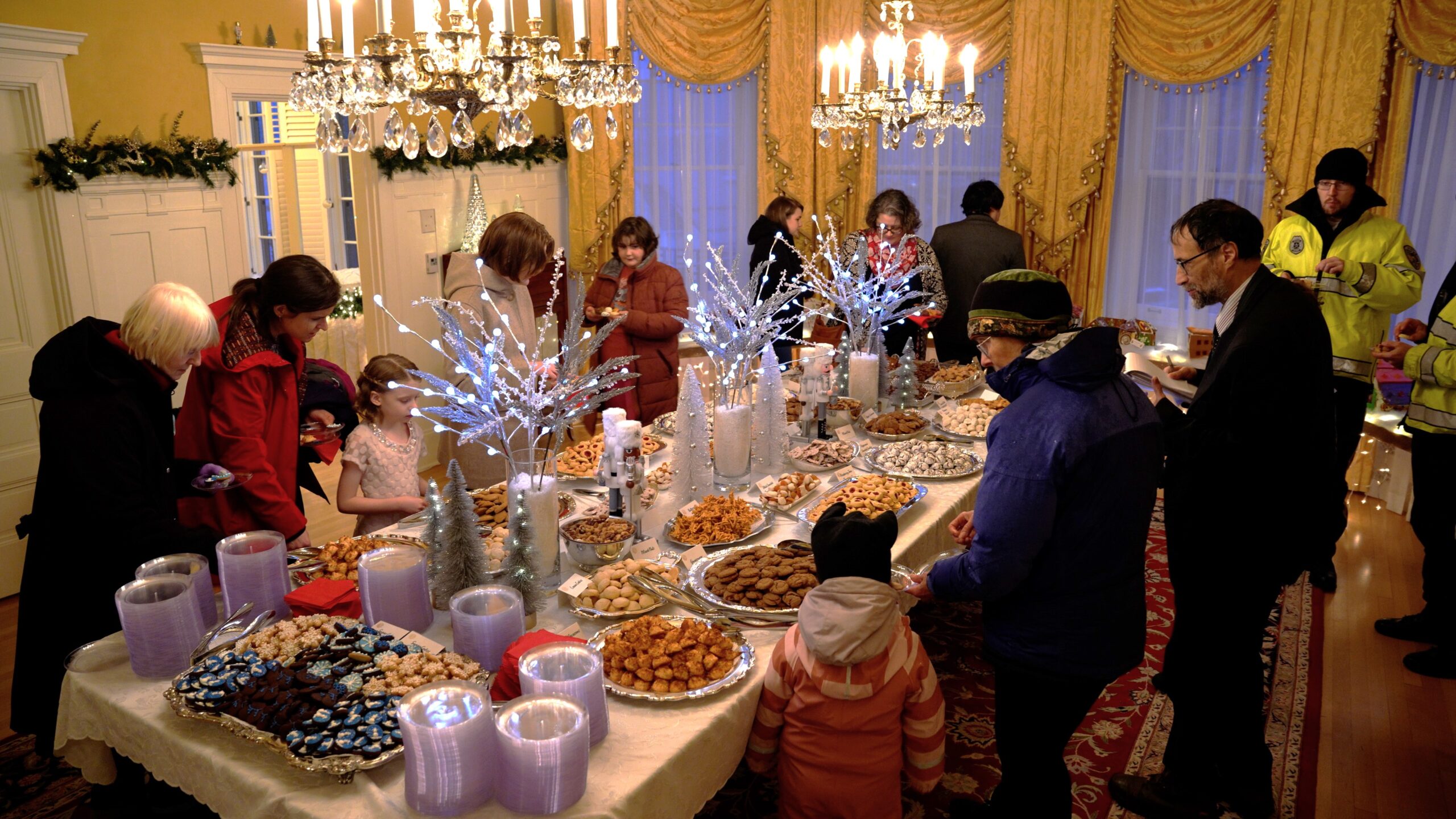 People taking holiday cookies from a large table