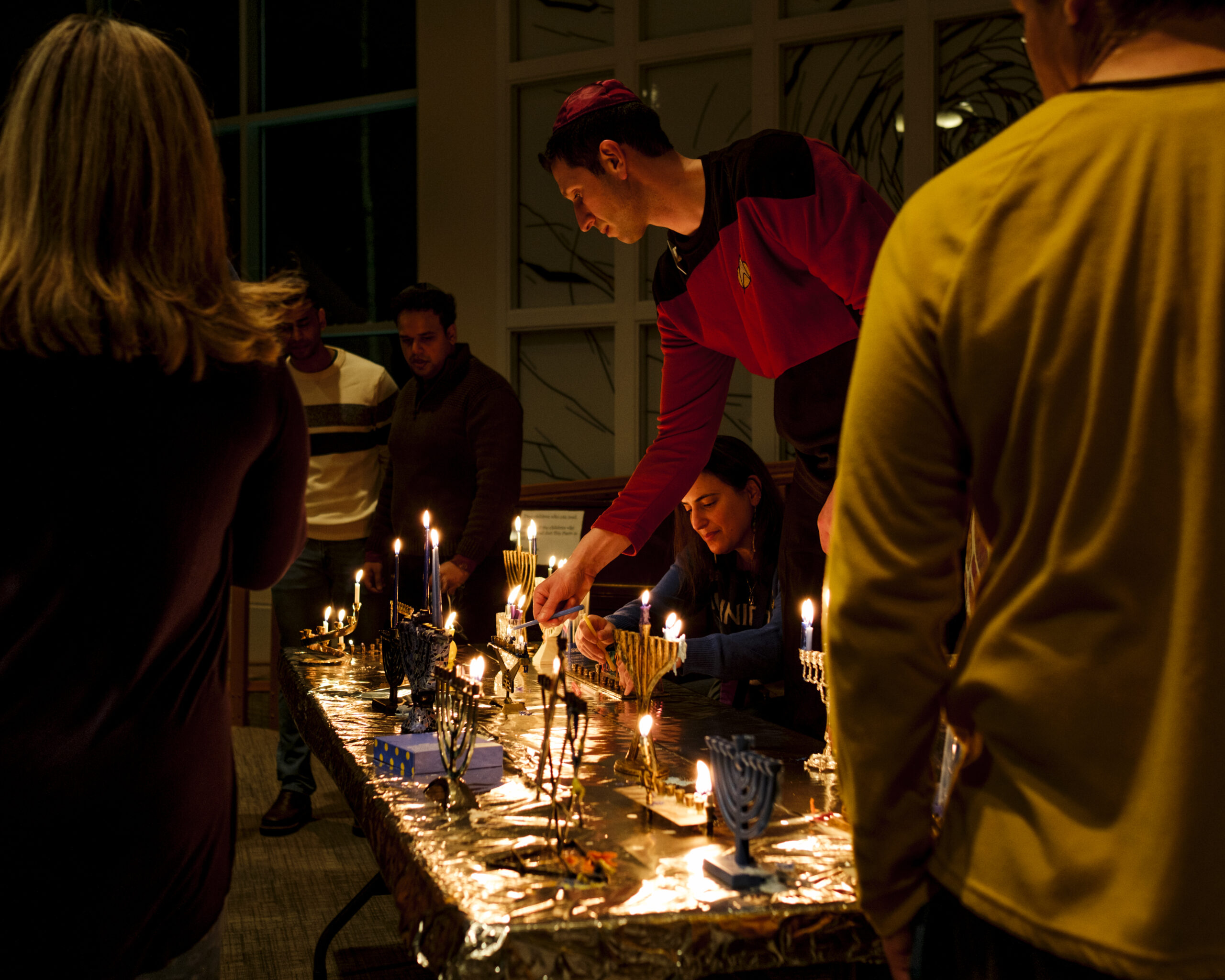 A man lights the candles on a menorah
