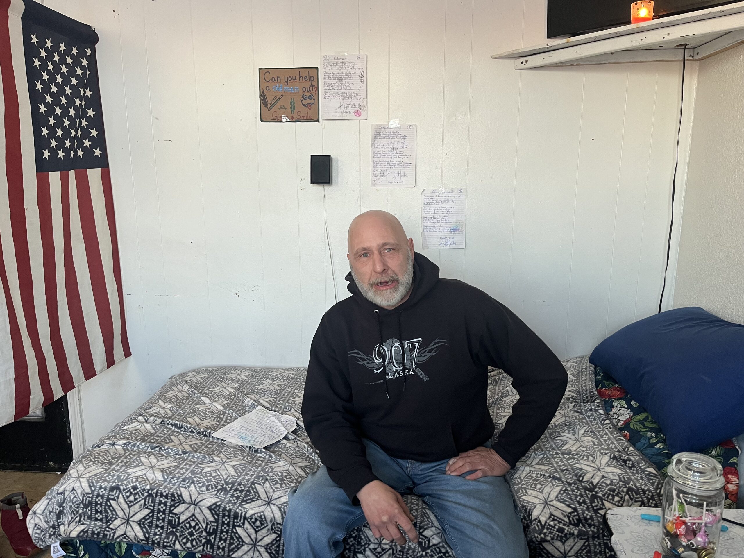 A man sits on a bed in his room
