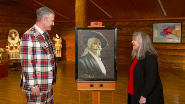 Antiques Roadshow appraiser looking at poster art in a log cabin.