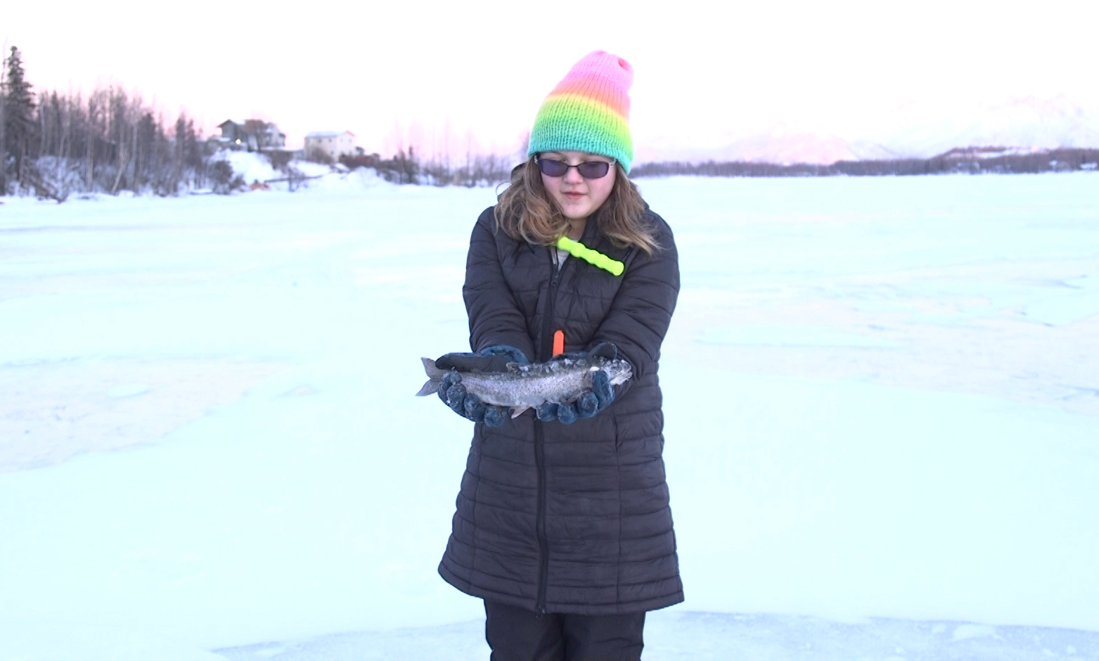 A middle school student proudly displays the fish she caught ice fishing on Wasilla Lake.