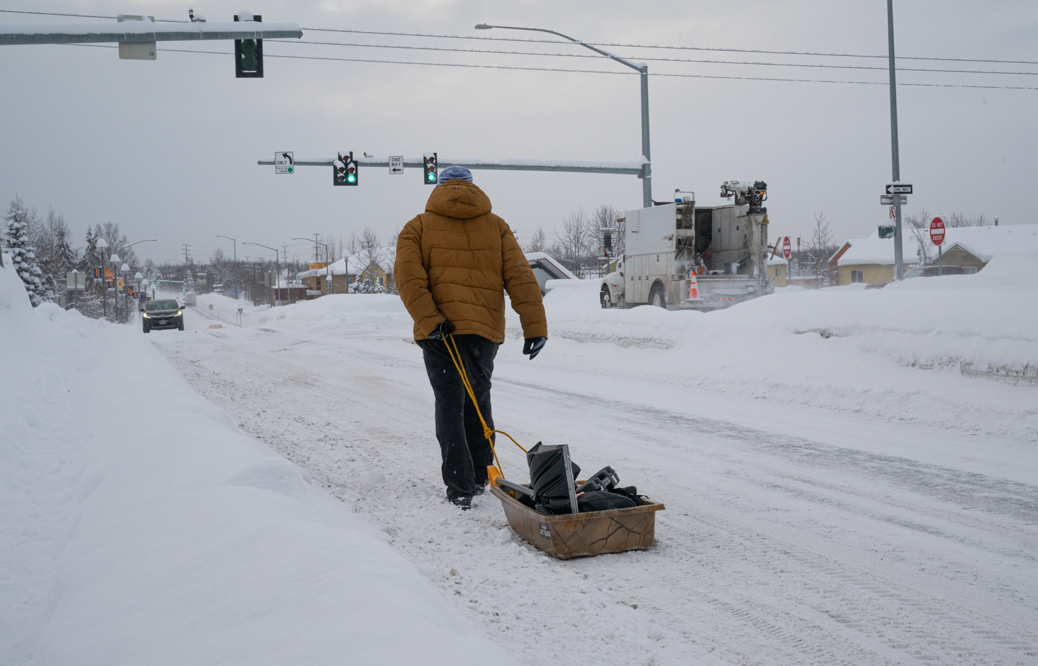 A man carries a sled full of shovels in winter.