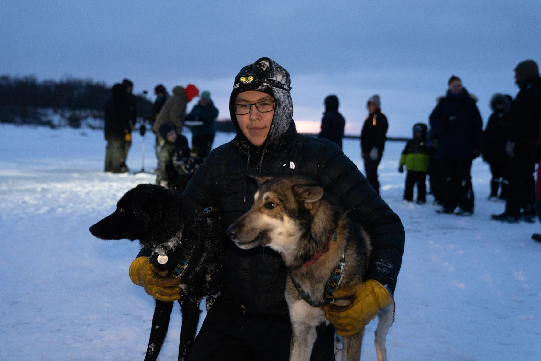 a musher poses with two sled dogs