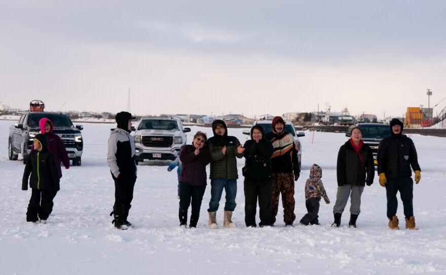 a group of people stand out in the snow, near a truck