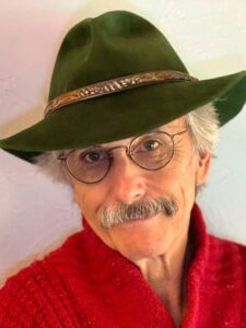 A man with a mustache in glasses, a red sweater and a green hat. 