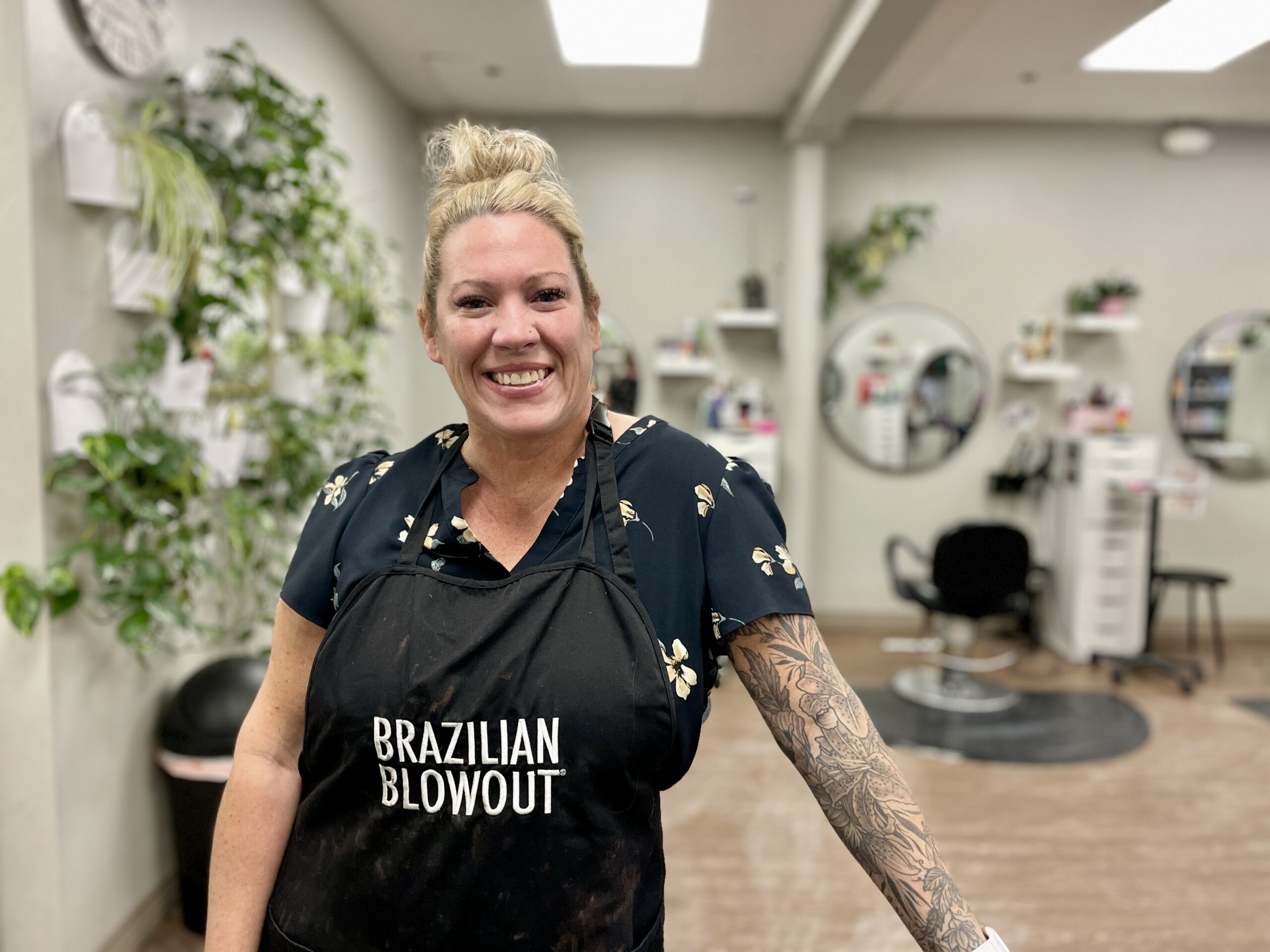 a woman at a hair salon, wearing an apron that says "Brazilian Blowout"