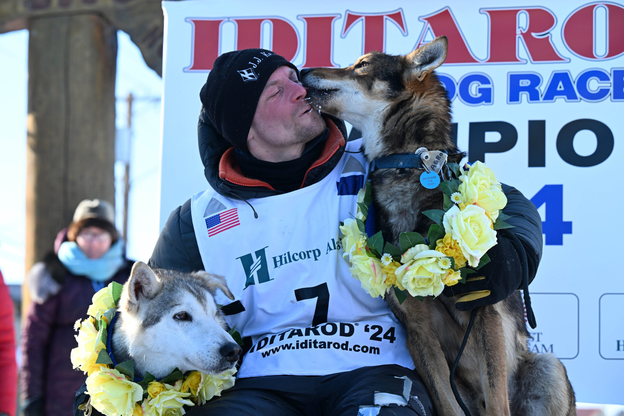 a musher gets a kiss from a dog