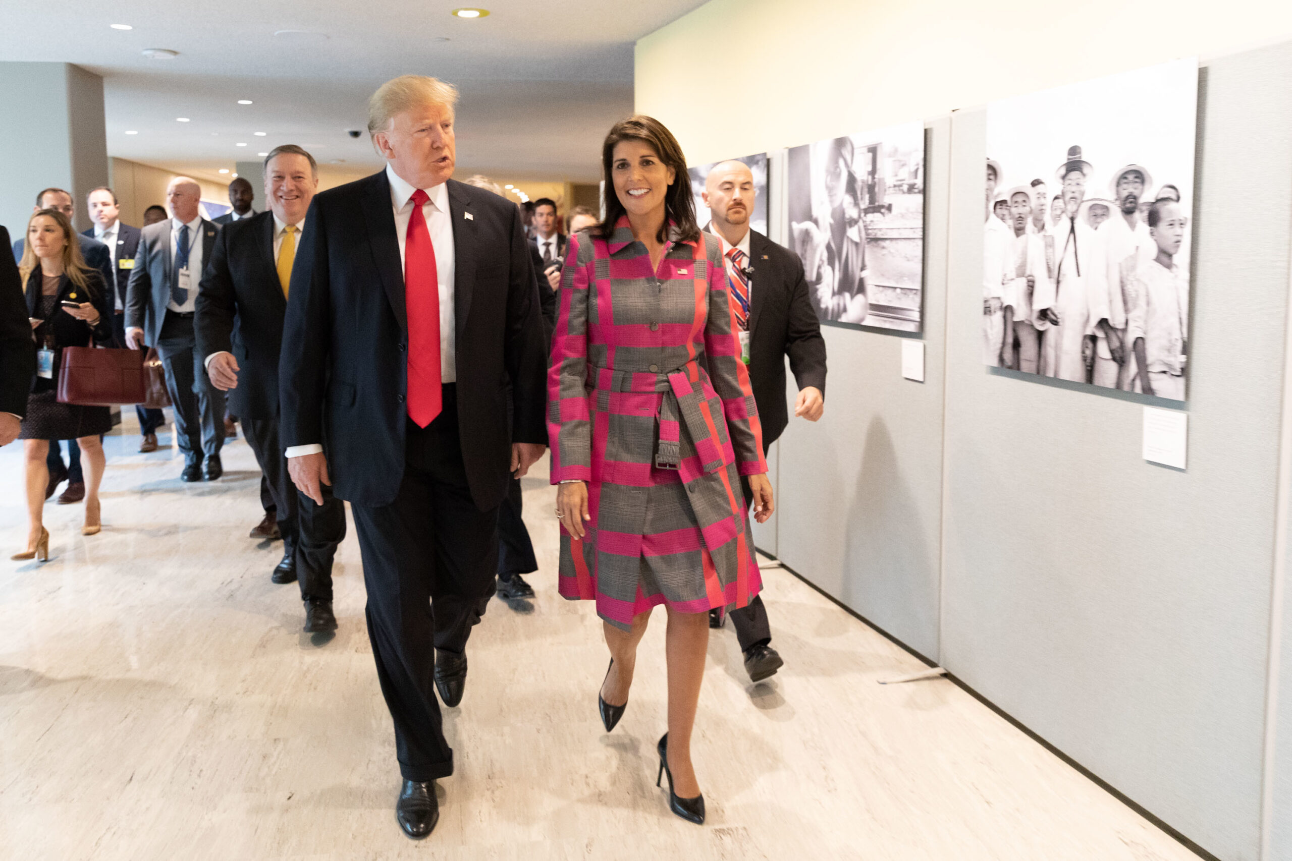 man and woman in business attire walk down a hallway
