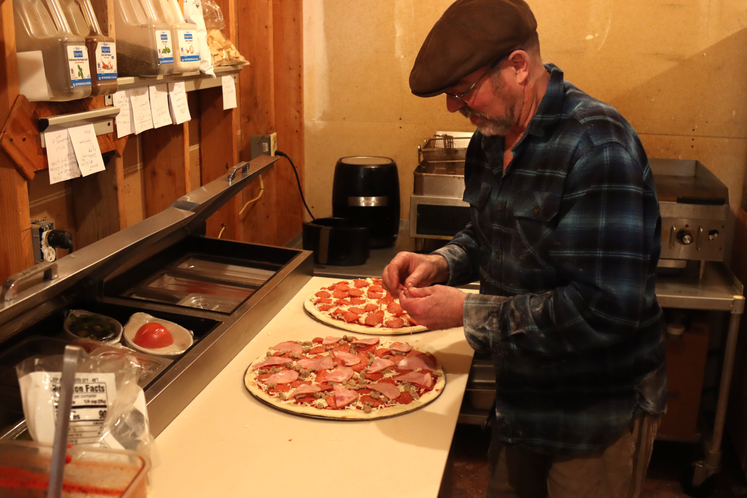 a man puts pepperoni on a pizza