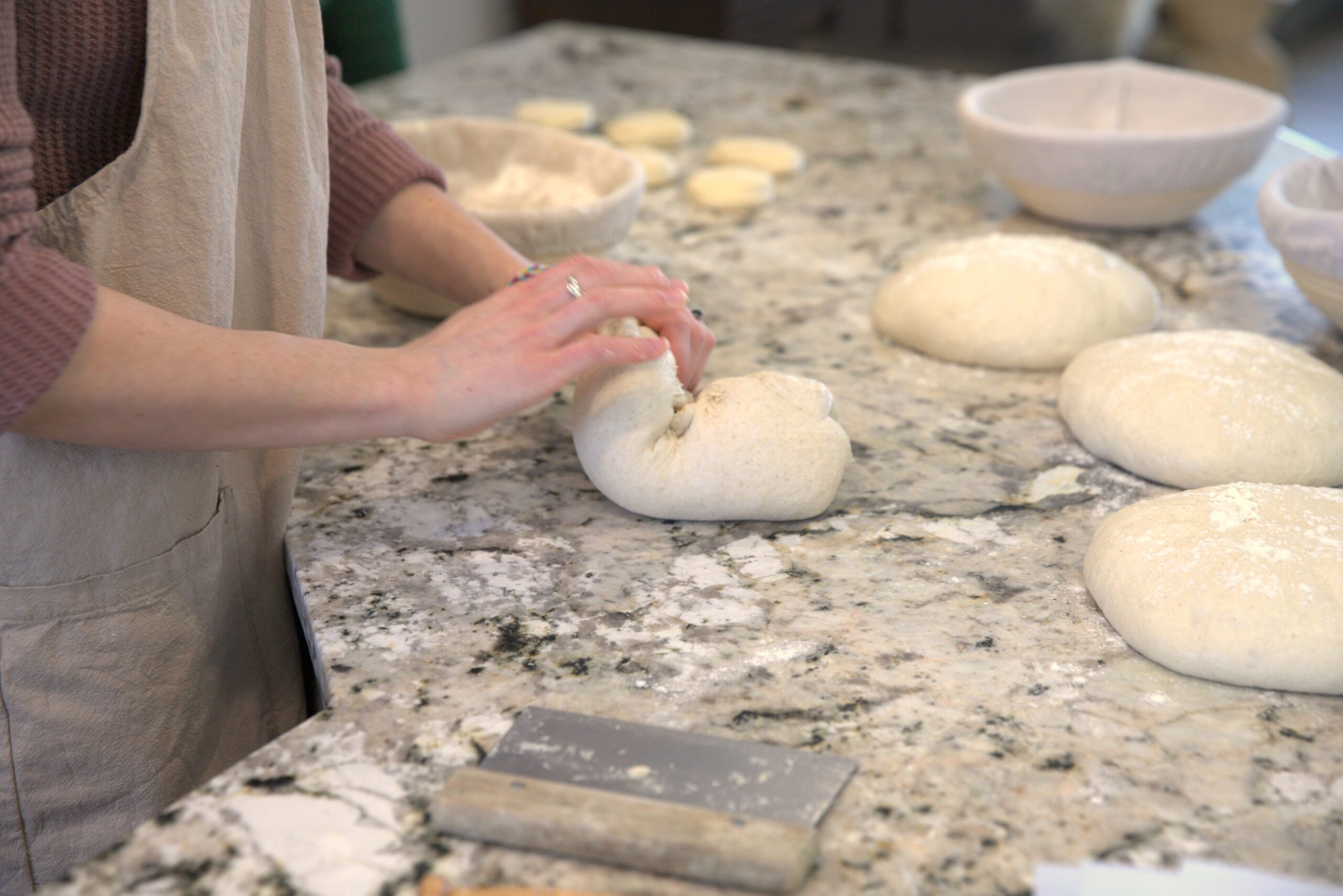 a woman folds dough on her kitchen counter
