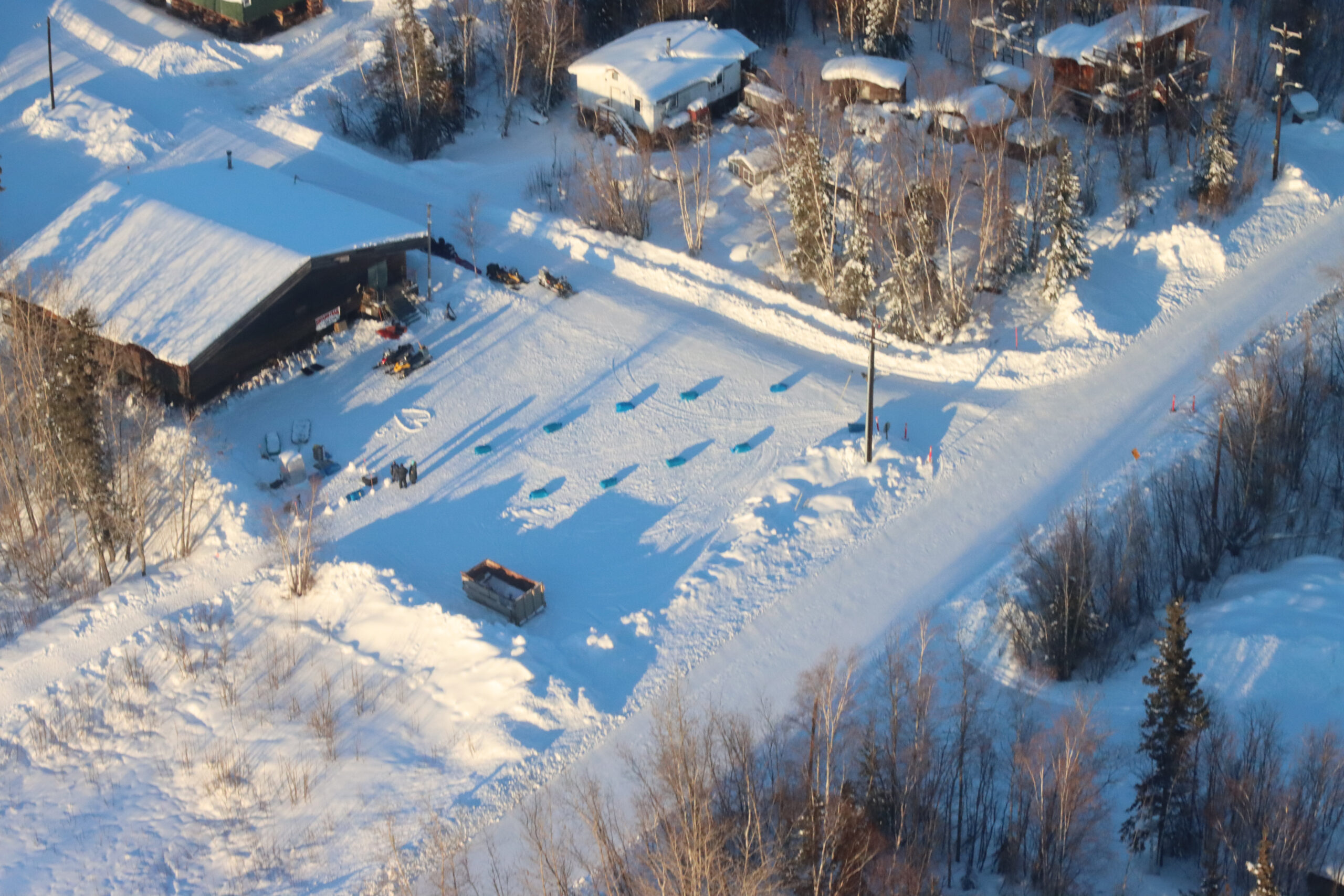 an aerial view of a snowy parking lot and road with straw bales laid out