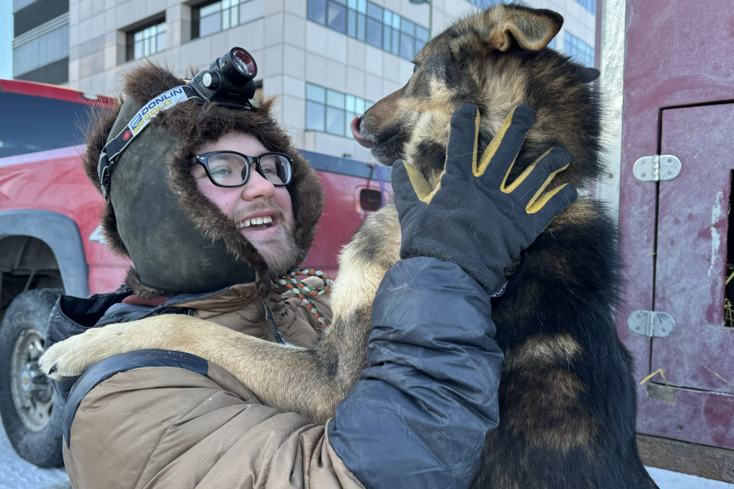 a musher and a dog look at each other