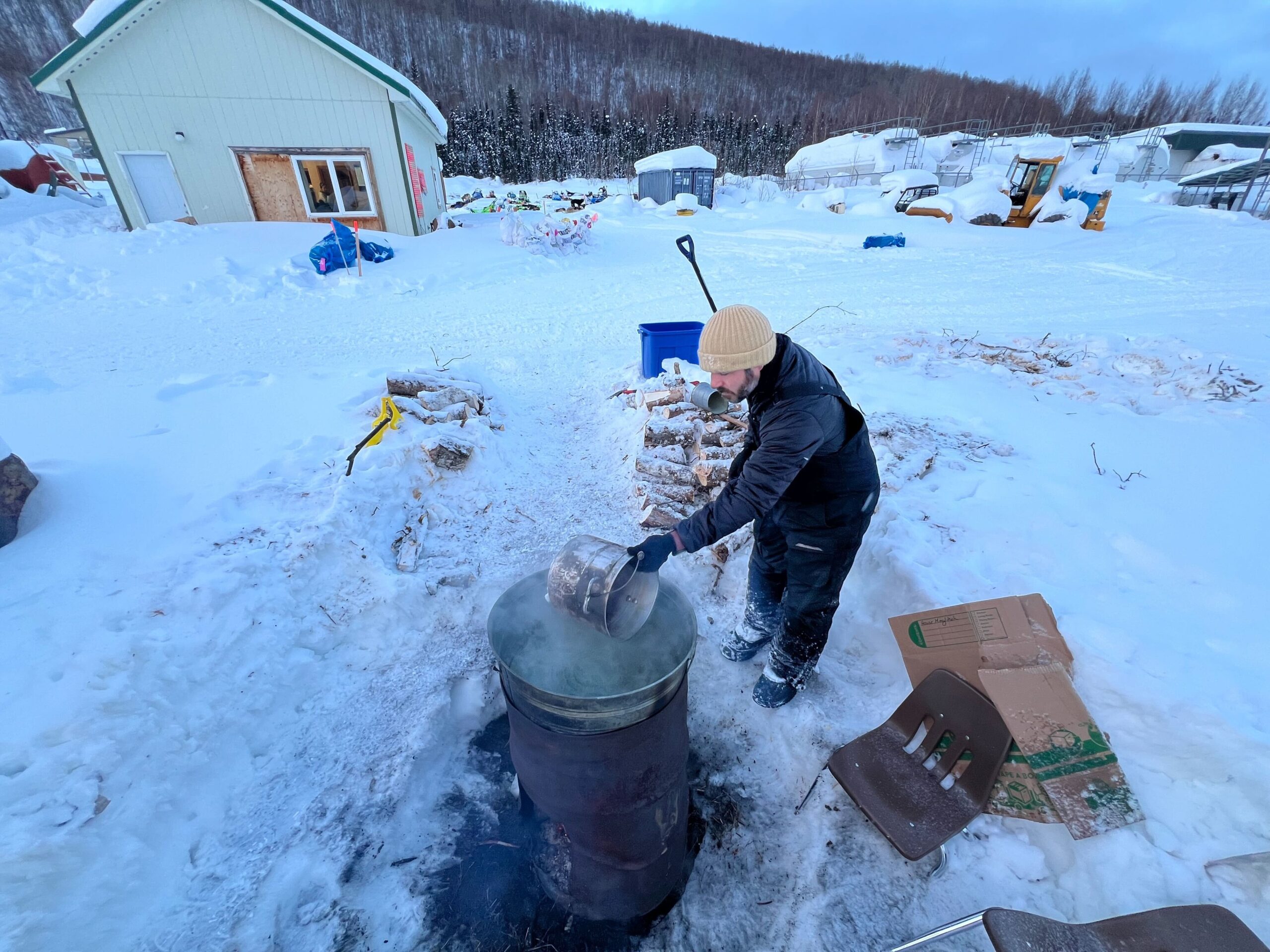 a musher gets hot water from a bucket