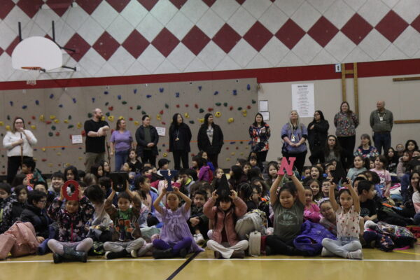 Students at Alaska Native Cultural Charter School hold up letters that read "quyana" during an assembly.
