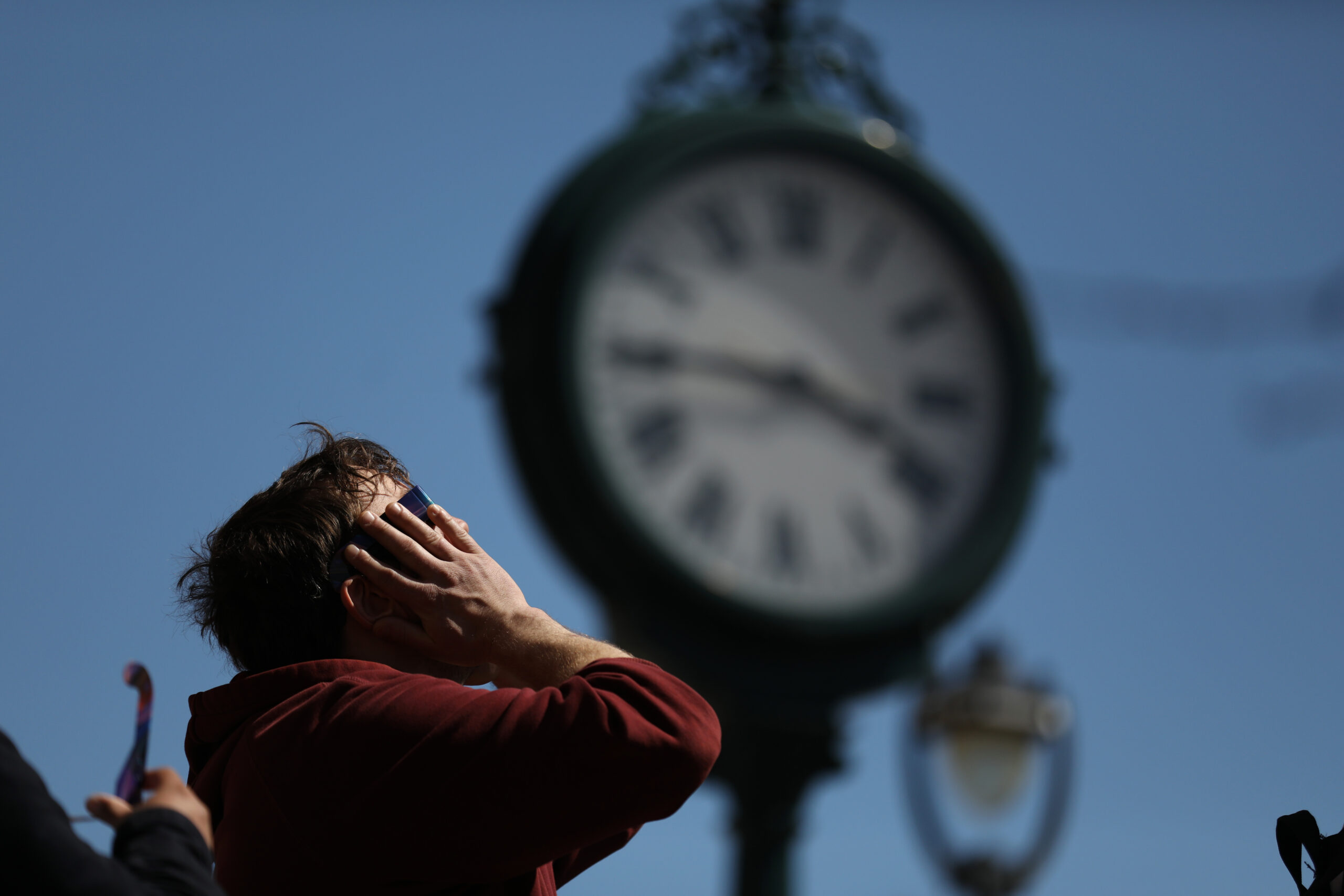 a person looks at the sky, in front of a clock