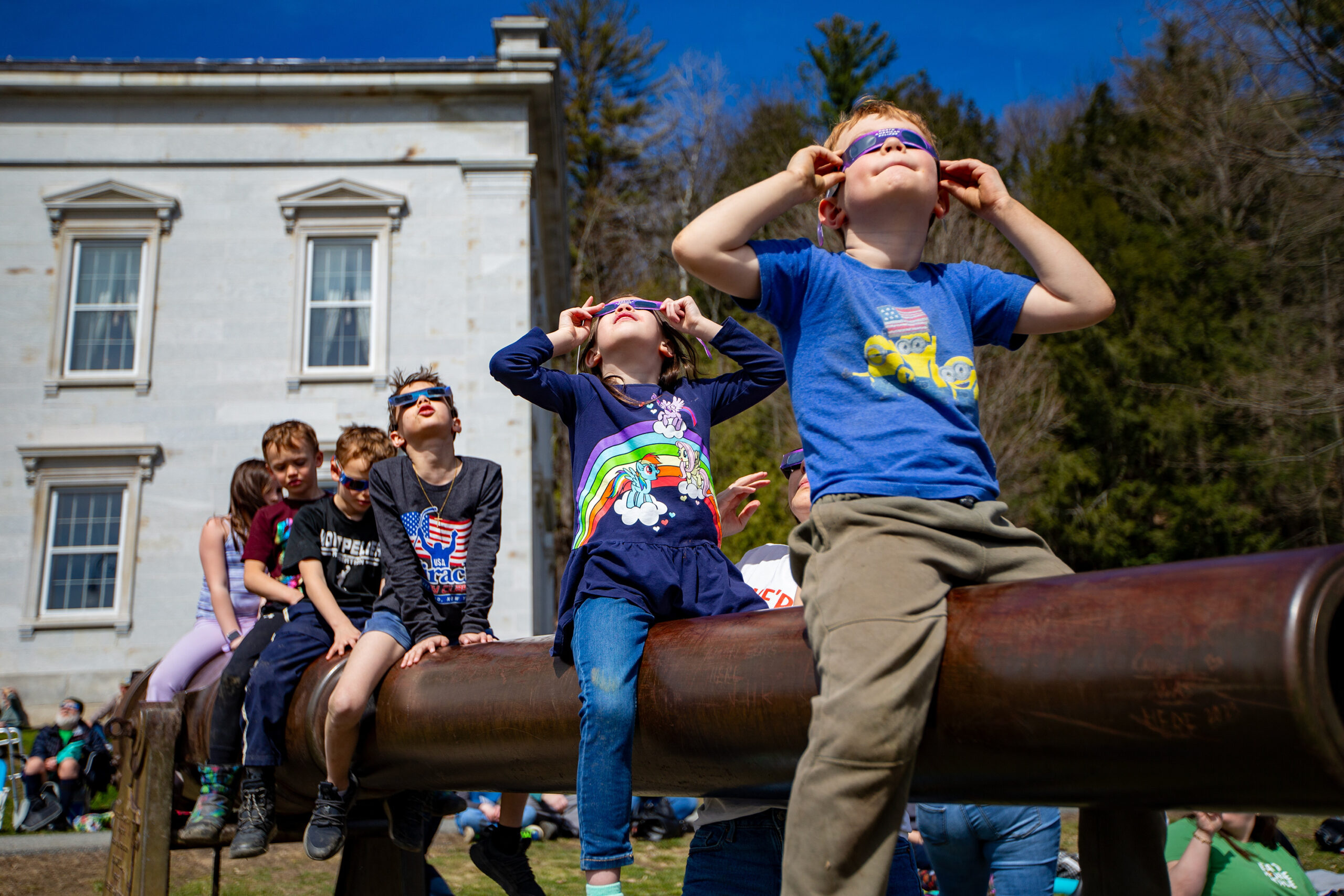 kids sit on a defunct cannon, watching the eclipse